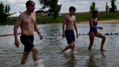 Gavin Maitland and his two children walking into a lake for a swim