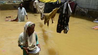 A Pakistani woman walks through floodwaters following heavy monsoon rain in Karachi on August 5, 2013