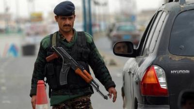 A Yemeni soldier checks vehicles