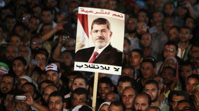 Supporters of deposed Egyptian President Mohamed Morsi hold up a poster of Morsi during a protest at the Rabaa al-Adawiya square where they are camping, in Cairo, 6 August, 2013.