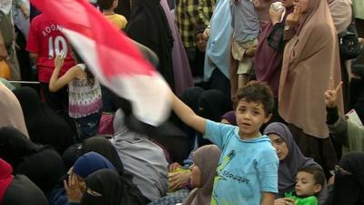 Boy waving Egyptian flag in crowd of mothers and children