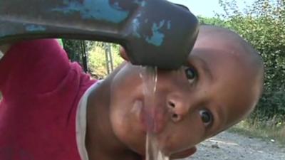 Child drinking from roadside water pump