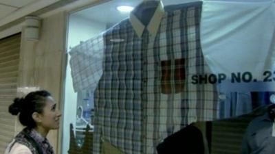 Anita Rani looks at a shirt in an over-size clothes shop in Mumbai