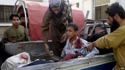 Pakistani bystanders help an injured Muslim youth as he sits in a pickup truck amidst bodies outside a hospital in Quetta on 9 August, 2013, following an attack by gunmen on a mosque.