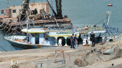 Police officers inspect a boat that was toed to the port of Catania, southern Italy