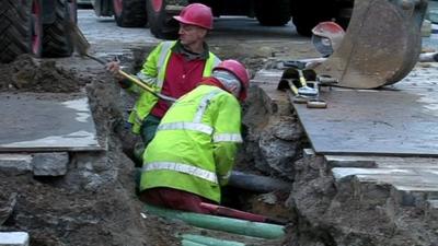 Workmen digging around pipes