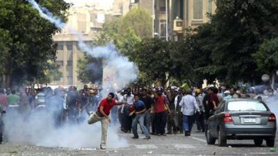 A supporter of ousted President Mohamed Morsi throws a tear gas canister back towards the police during clashes in central Cairo August 13, 2013