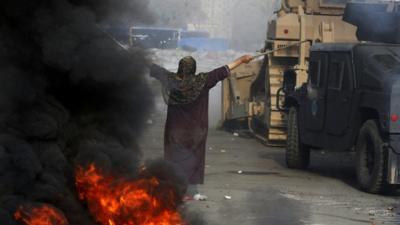 An Egyptian woman gestures in front of a military bulldozer