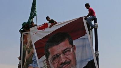 Lebanese supporters of the Islamic Group, a Lebanese faction linked to the Muslim Brotherhood, install a big portrait of ousted Islamist President Mohammed Morsi at a street advertising board during a protest at the Egyptian Embassy in Beirut, Lebanon