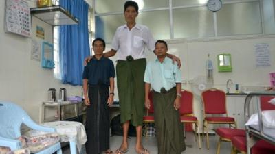 Win Zaw Oo standing next to two men of average height