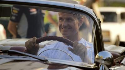 British former Formula One racing driver, sits behind the wheel of a 1955 Pontiac convertible car