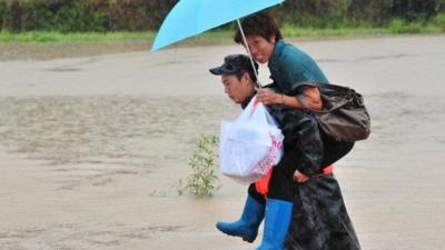 People cross river in flooded China