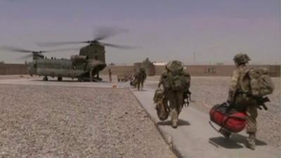 British troops carry bags to an Apache helicopter