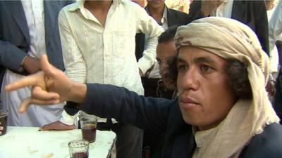 A Yemeni man, amongst a group of men talking about how US bombing has affected their lives