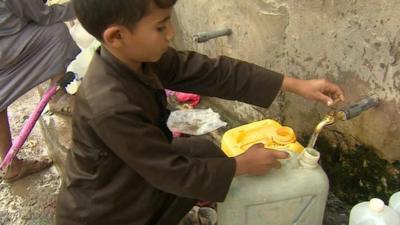 Young boy filling container with water