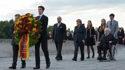 German Chancellor Angela Merkel (C-R) lays a wreath alongside Holocaust survivor and author Max Mannheimer