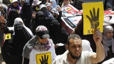 Supporters of Muslim brotherhood hold up posters showing 'Rabaa' gesture