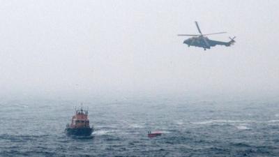 Rescuers approaching a liferaft from the crashed helicopter