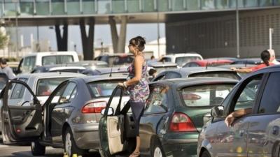 Woman standing by car in middle of traffic