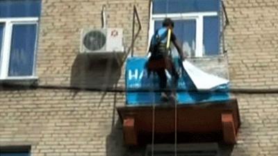 Screengrab from news site Lenta, showing an abseiler tearing a banner from a balcony