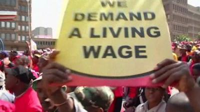 Protestors holding placards that read 'we demand a living wage'