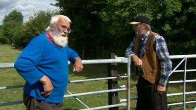 Two men leaning on gates