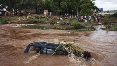 People look at a SUV submerged in floodwaters in Bamako