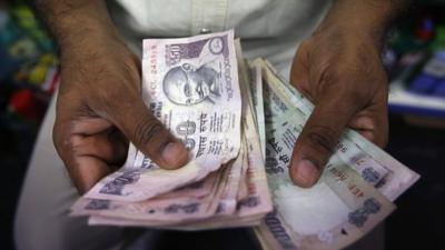 A man counts Indian Rupee currency notes at a shop in Mumbai