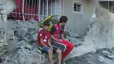 Boys sit in the rubble of a building in Baghdad