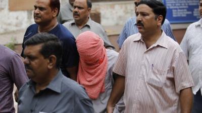 The teenager convicted of taking part in a fatal gang rape is escorted by police outside the Juvenile justice board in New Delhi