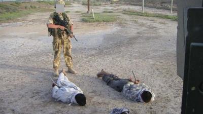 Detained Iraqis being guarded by a British soldier, as shown at the The Al-Sweady Inquiry