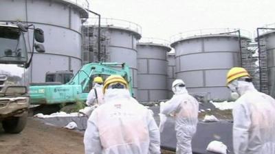 Workers at the Fukushima plant wearing white radiological protection suits, masks and hard hats