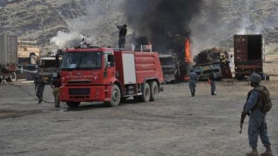 Afghan security personnel stand alert near burnt military vehicles after the clash