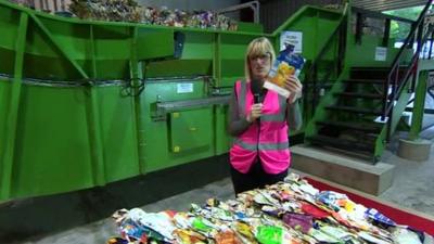 Steph McGovern holds carton at recycling plant