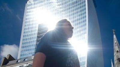 Woman walks through shaft of light from "Walkie Talkie" skyscraper