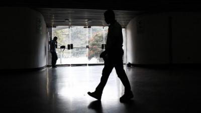 A security guard walks past an exit door as he waits for the power to return after a blackout during the FIBA Americas Championship basketball game between Paraguay and Dominican Republic in Caracas September 3, 2013