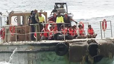 People wearing orange life jackets aboard a boat.