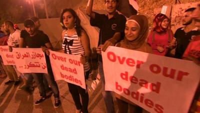 Syrians holding banners saying 'Over our dead bodies'