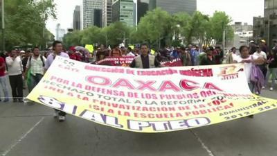 Protesters in Mexico City march with a banner opposing education reforms.