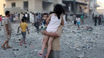 A man carries two children away from the scene of an explosion in the northern Syrian city of Raqqa