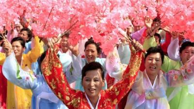 North Korean women hold up flowers during a military parade at Kim Il Sung Square, Pyongyang to mark the 65th anniversary of the country's founding