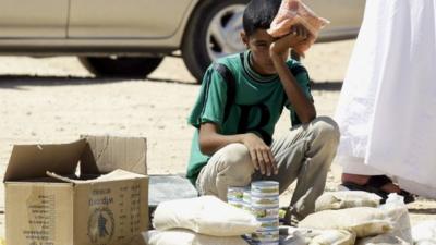 Boy selling cans of tuna in Zaatari refugee camp, Jordan