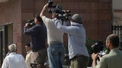 Photojournalists take pictures of a Delhi police van believed to be carrying the accused