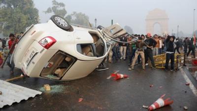 In December 2012, Indian demonstrators look on after turning over a car during a protest in front of the India Gate monument in New Delhi, calling for better safety for women following the rape of a student in the Indian capital