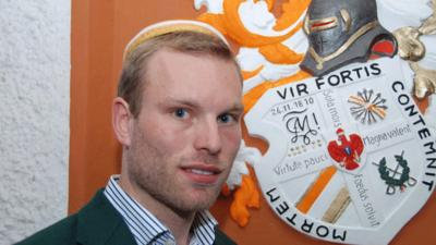 German student fencer Nils Hempel stands in front of the coat of arms of his fraternity in Berlin, the Corps Marchia