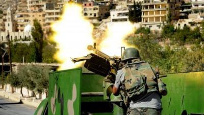 a Syrian military solider fires a heavy machine gun