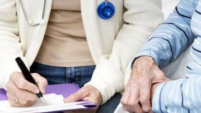 GP and elderly patient filling in form