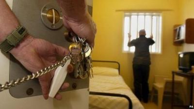 A prison warder locks a prisoner in a prison cell