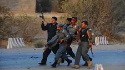 Afghanistan security forces carry a wounded police officer during an attack on the US consulate in Herat on 13 September 2013