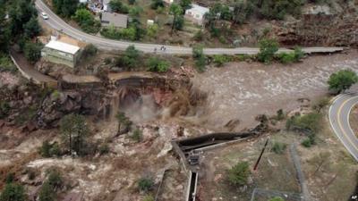 This aerial photo shows a raging waterfall destroying a bridge along Highway 34 toward Estes Park, Colo